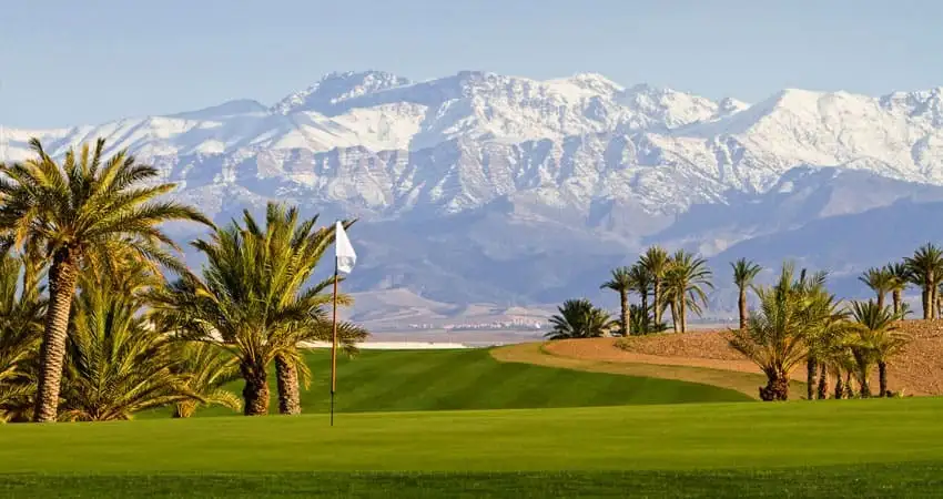 Desert-style fairway at Assoufid Golf Club, Marrakech, with the High Atlas Mountains behind